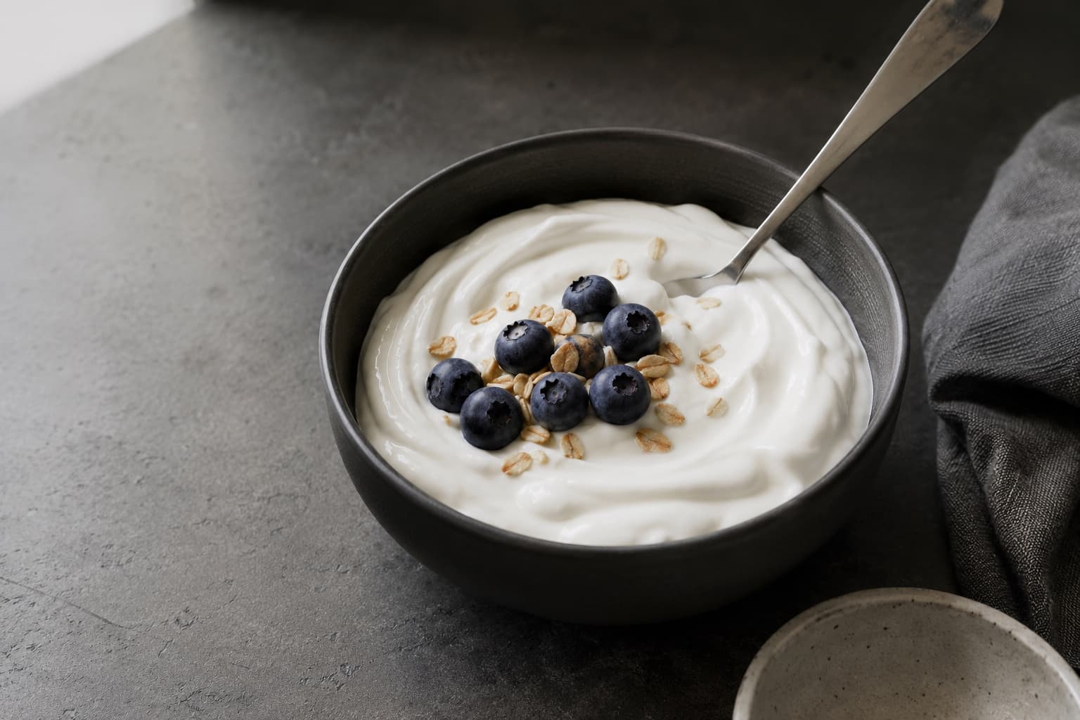 Plain Greek yogurt in a white bowl, thick enough to hold the mark of a spoon